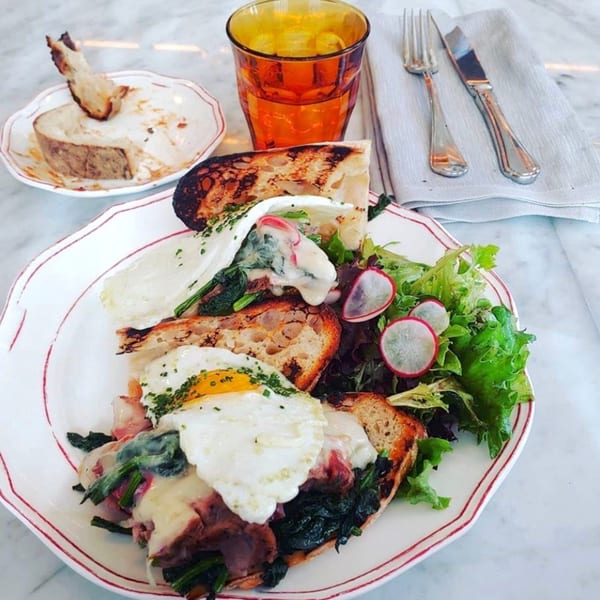 Officina's Italian breakfast with fried eggs, spinach, cheese, and toast, served with a side salad.