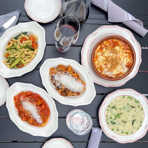 Overhead view of various Italian pasta dishes, including risotto, on a dark table at Officina.