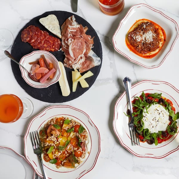 An Italian spread with charcuterie, cheeses, pickled vegetables, pasta, burrata, and grain salad.