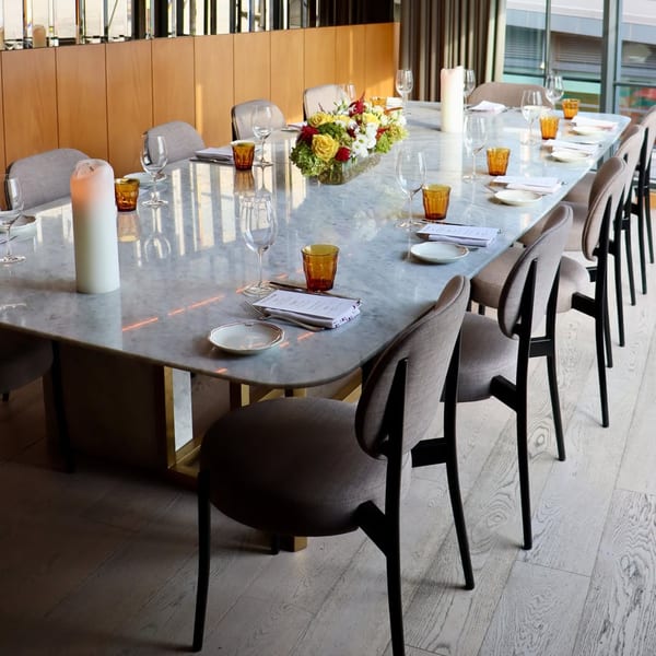 Long marble dining table set with place settings, candles, and a floral centerpiece at Officina.