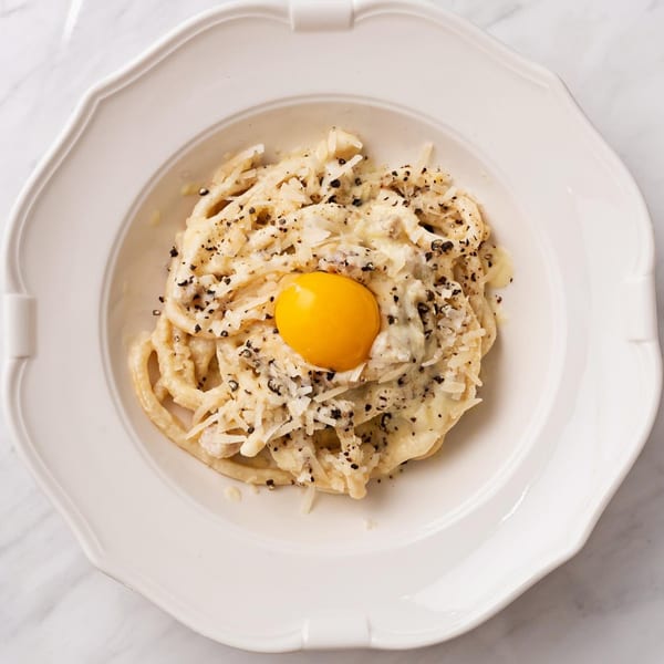 Officina's Cacio e Pepe pasta with a bright orange egg yolk, grated cheese, and black pepper.