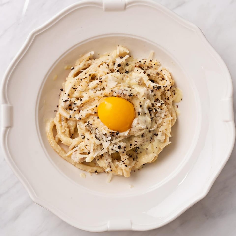 Officina's Cacio e Pepe pasta with a bright orange egg yolk, grated cheese, and black pepper.