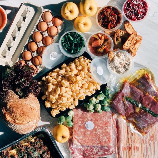 Overhead view of Officina Italian meal kit ingredients including pasta, meats, eggs, bread, and prepared dishes.