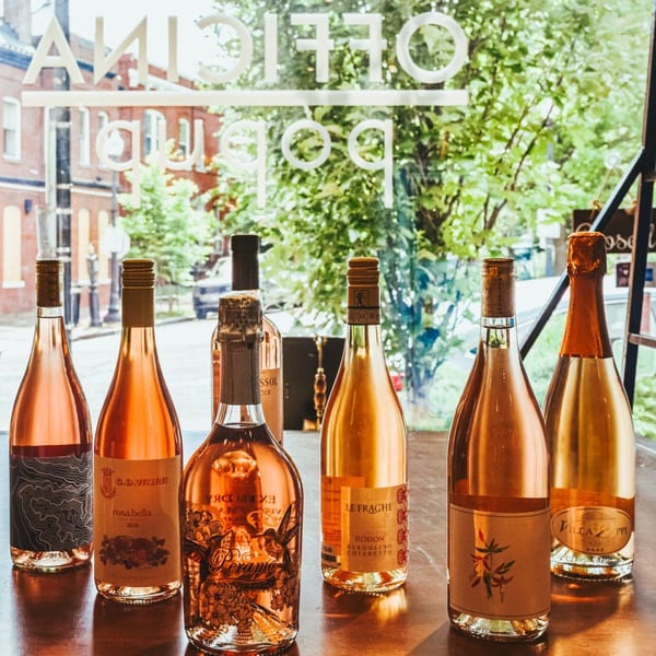 A collection of rose wine bottles from Officina, with the restaurant name visible on the window.